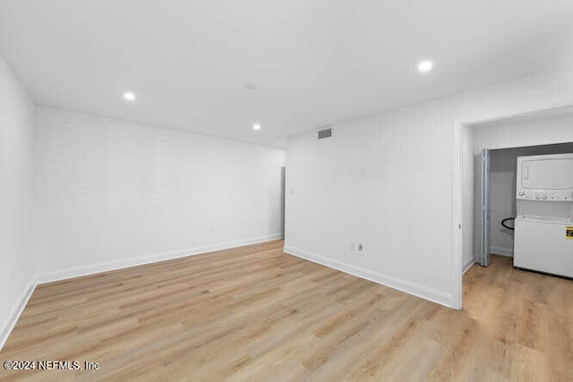 spare room featuring light hardwood / wood-style floors and stacked washer / drying machine