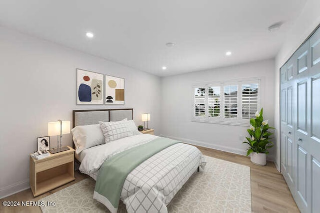 bedroom with light hardwood / wood-style floors and a closet