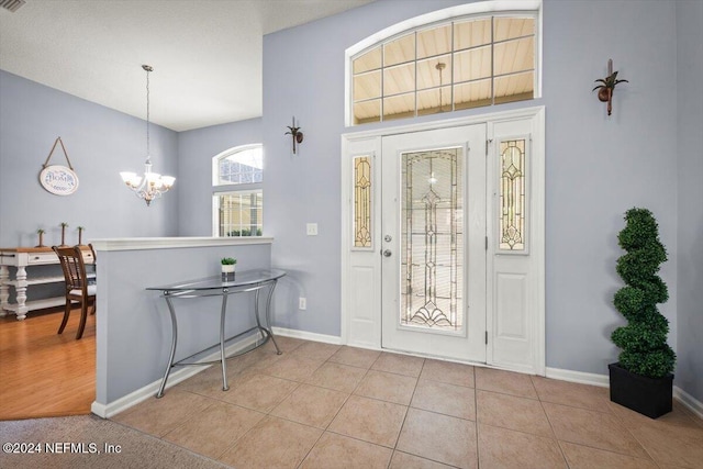 tiled foyer entrance with an inviting chandelier