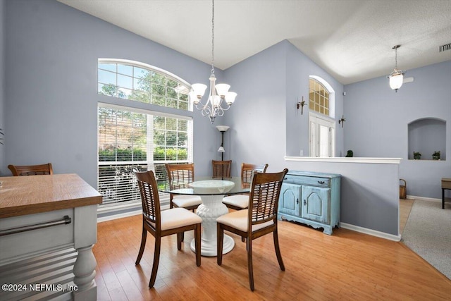 dining room with light hardwood / wood-style flooring, vaulted ceiling, and a notable chandelier