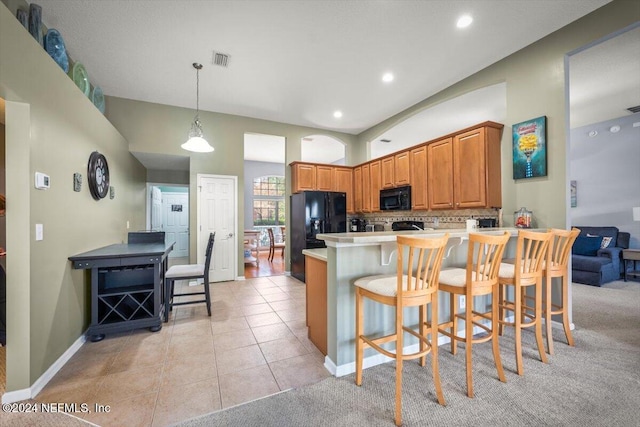 kitchen with hanging light fixtures, backsplash, a breakfast bar, light tile patterned floors, and black appliances