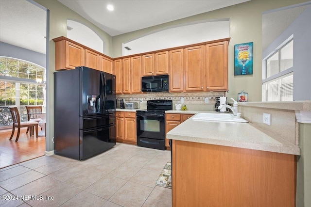 kitchen with black appliances, sink, light tile patterned floors, tasteful backsplash, and kitchen peninsula