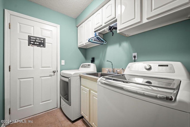 laundry room with cabinets, a textured ceiling, sink, light tile patterned floors, and washing machine and dryer