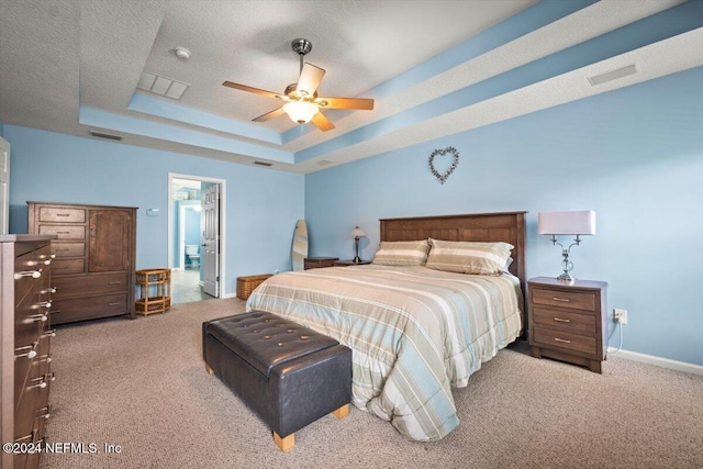 bedroom featuring carpet, a textured ceiling, a tray ceiling, and ceiling fan