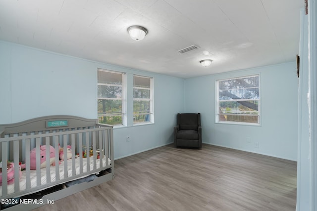 bedroom featuring hardwood / wood-style flooring, multiple windows, and a nursery area