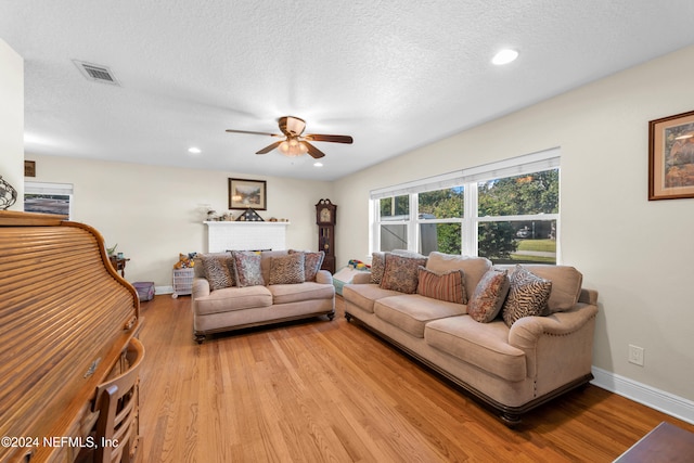 living room with ceiling fan, light hardwood / wood-style floors, and a textured ceiling