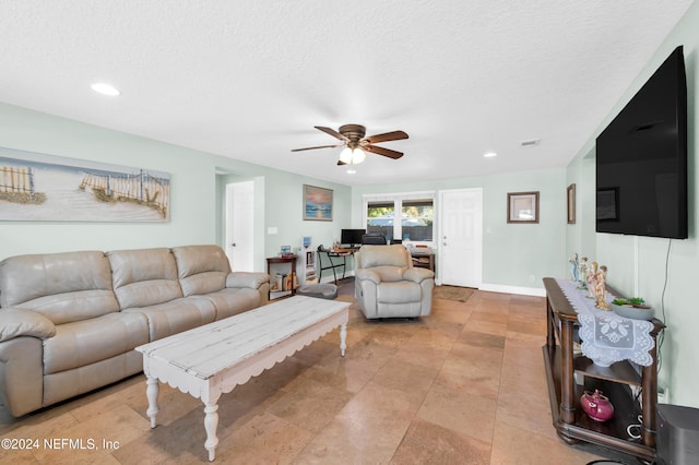 living room featuring ceiling fan and a textured ceiling