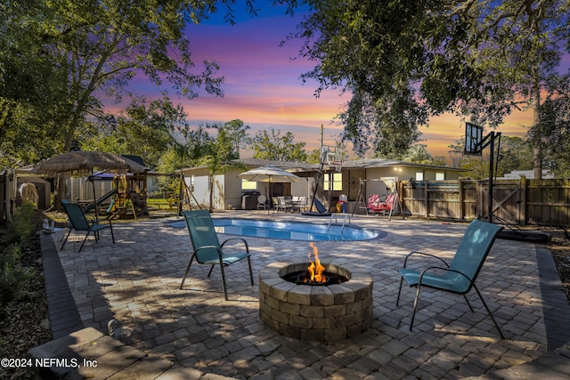 pool at dusk featuring a patio and a fire pit