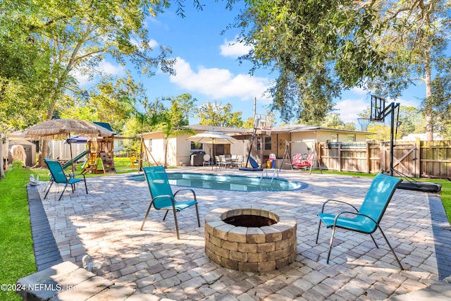 view of pool featuring a playground, a patio area, and a fire pit