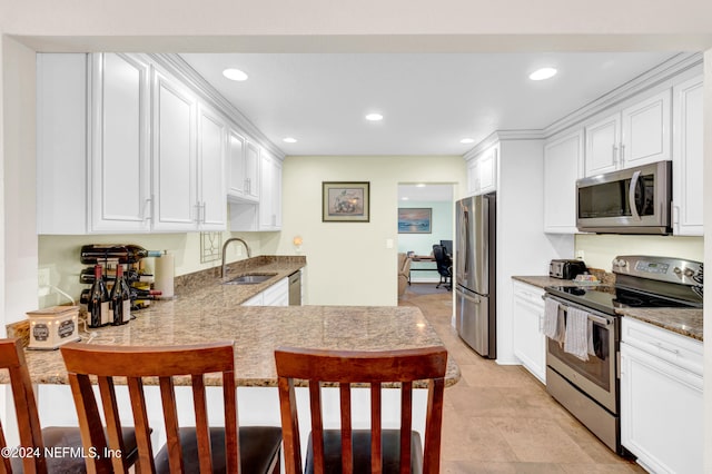 kitchen with white cabinets, kitchen peninsula, sink, and appliances with stainless steel finishes