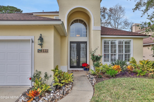 view of exterior entry featuring french doors and a garage