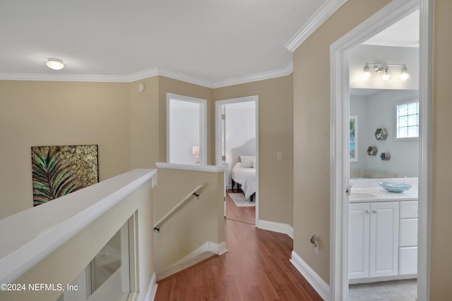 hallway featuring light wood-type flooring, ornamental molding, and sink