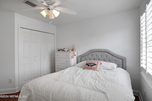 bedroom with multiple windows, ceiling fan, a closet, and hardwood / wood-style flooring