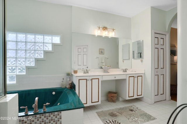 bathroom with tile patterned floors, vanity, and a relaxing tiled tub