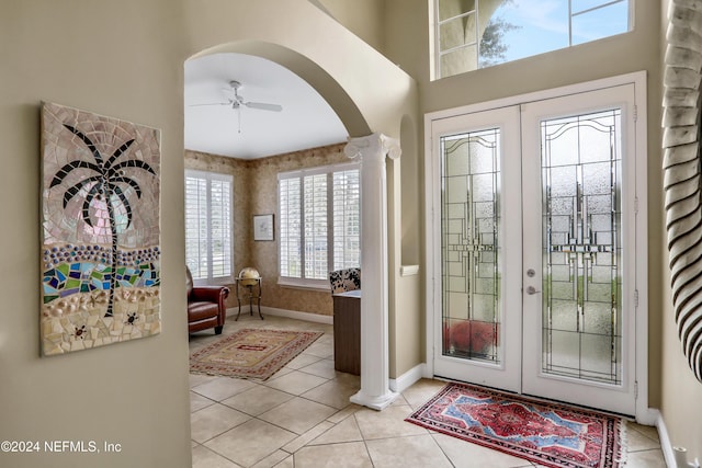 tiled entryway with decorative columns, ceiling fan, french doors, and a healthy amount of sunlight