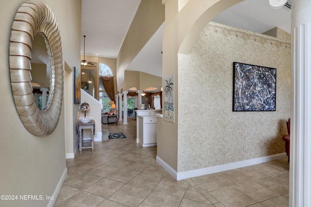 foyer featuring ceiling fan, light tile patterned floors, and a high ceiling