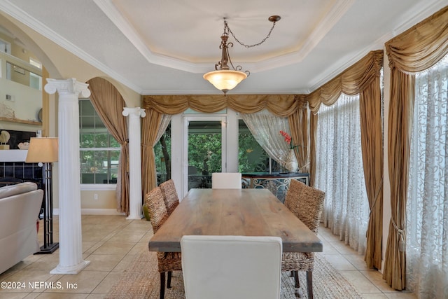 tiled dining area featuring a raised ceiling, crown molding, and decorative columns