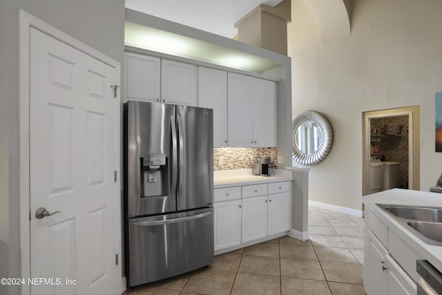 kitchen featuring white cabinets, light tile patterned flooring, washer / dryer, and stainless steel appliances