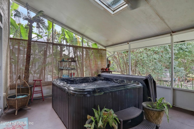 sunroom / solarium featuring a jacuzzi, a healthy amount of sunlight, and vaulted ceiling with skylight