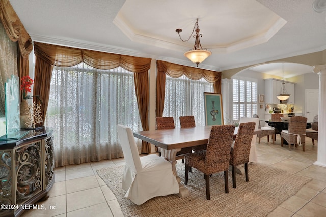 dining area featuring decorative columns, a tray ceiling, and light tile patterned flooring