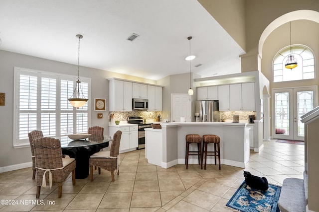 dining area with a healthy amount of sunlight, light tile patterned floors, high vaulted ceiling, and french doors