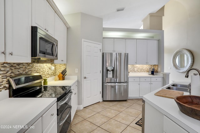 kitchen featuring sink, stainless steel appliances, light tile patterned floors, tasteful backsplash, and white cabinets