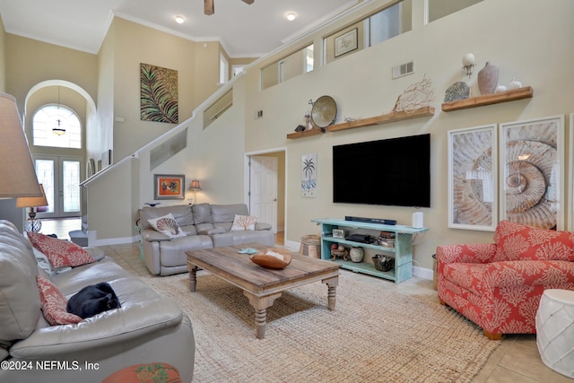 tiled living room featuring ceiling fan, crown molding, a high ceiling, and french doors