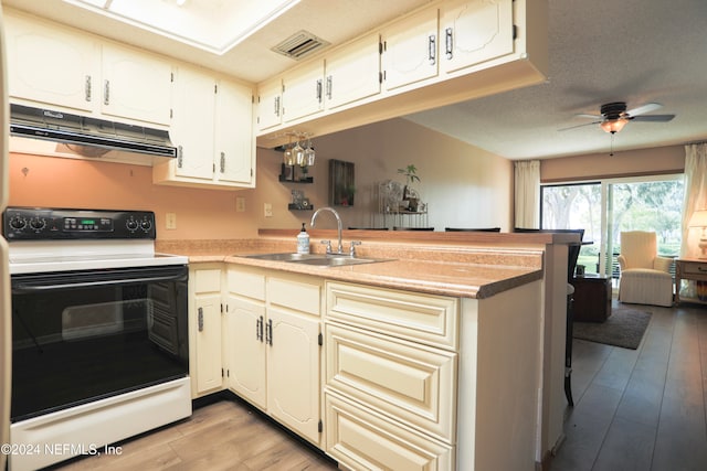 kitchen with kitchen peninsula, sink, light hardwood / wood-style floors, and electric stove