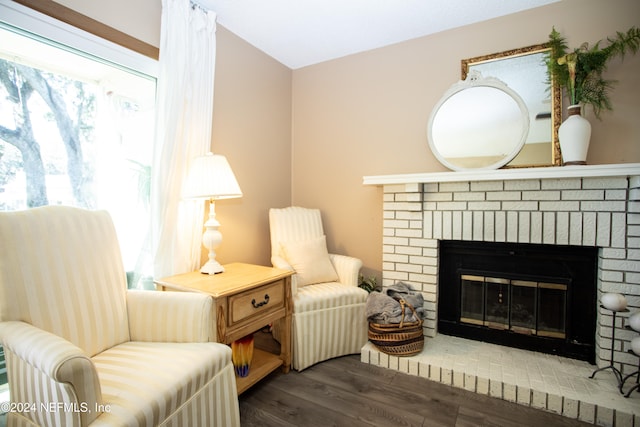 sitting room featuring dark wood-type flooring and a brick fireplace