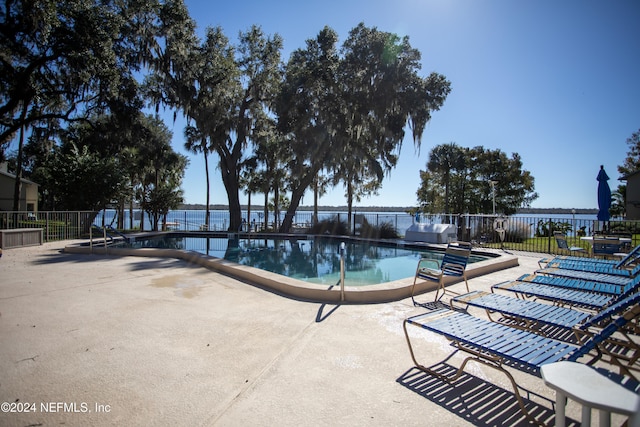 view of swimming pool with a patio and a water view