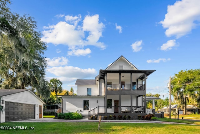 view of front facade with a balcony, a garage, a front lawn, and an outdoor structure