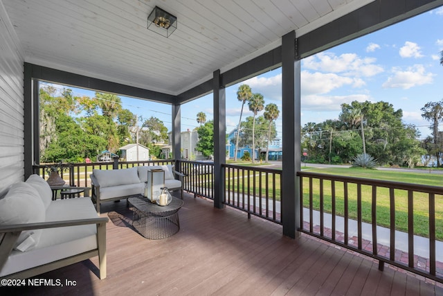 wooden terrace with a lawn and covered porch