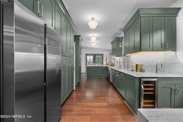 kitchen with dark wood-type flooring, beverage cooler, tasteful backsplash, appliances with stainless steel finishes, and green cabinetry