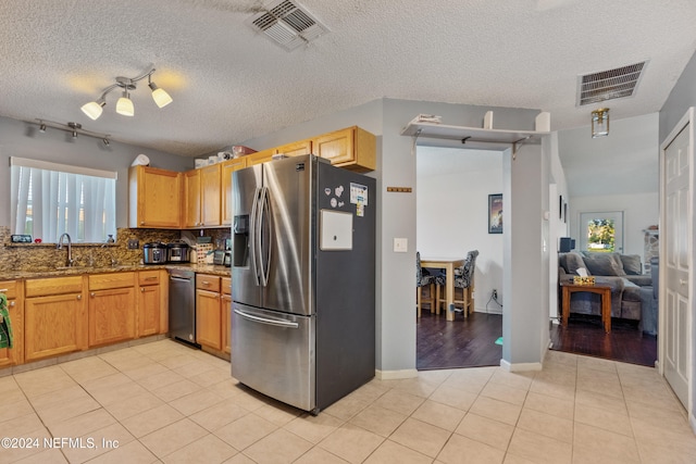 kitchen with backsplash, light tile patterned floors, dark stone counters, and appliances with stainless steel finishes