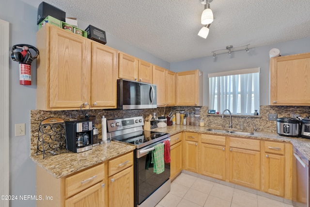 kitchen with light brown cabinets, a textured ceiling, stainless steel appliances, and sink