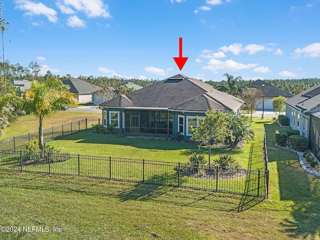 rear view of house featuring a yard and a sunroom