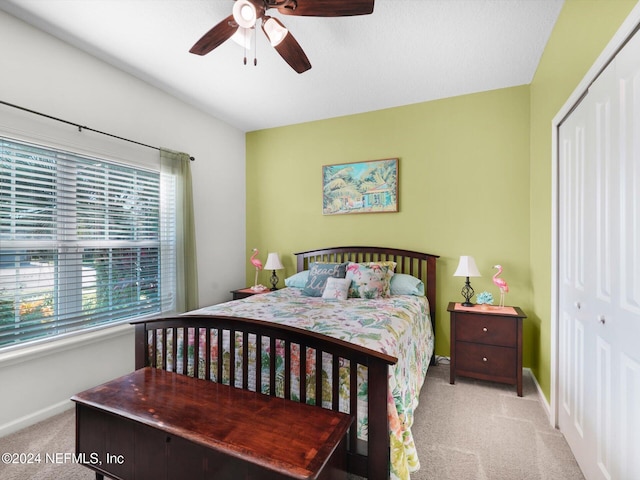 bedroom with ceiling fan, light carpet, and a closet