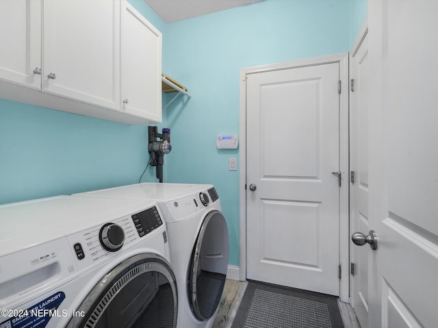 laundry area with cabinets, dark hardwood / wood-style floors, and washer and clothes dryer