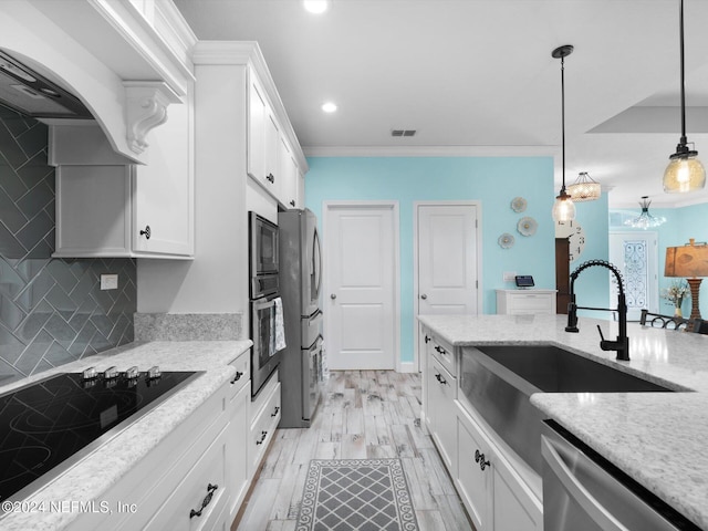 kitchen with light wood-type flooring, tasteful backsplash, stainless steel appliances, white cabinets, and hanging light fixtures