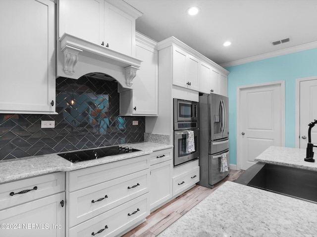 kitchen featuring white cabinets, decorative backsplash, light hardwood / wood-style floors, and appliances with stainless steel finishes