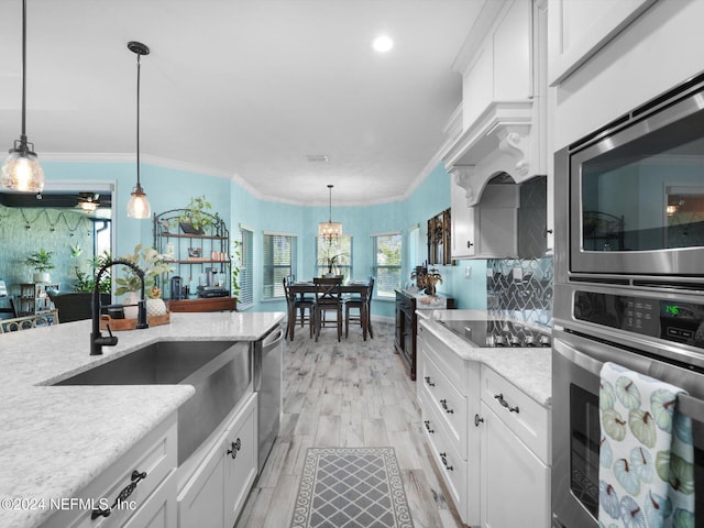 kitchen featuring appliances with stainless steel finishes, decorative light fixtures, and white cabinetry