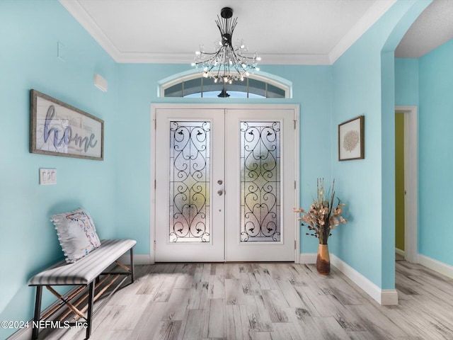 entrance foyer with french doors, light hardwood / wood-style flooring, ornamental molding, and a notable chandelier