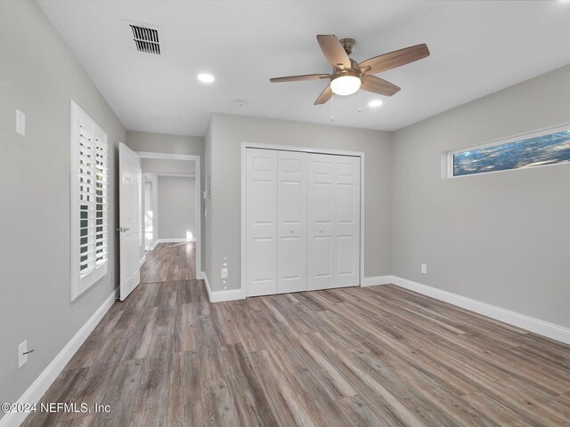 unfurnished bedroom featuring multiple windows, ceiling fan, and wood-type flooring