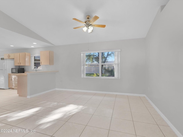 interior space featuring ceiling fan, light tile patterned flooring, and vaulted ceiling