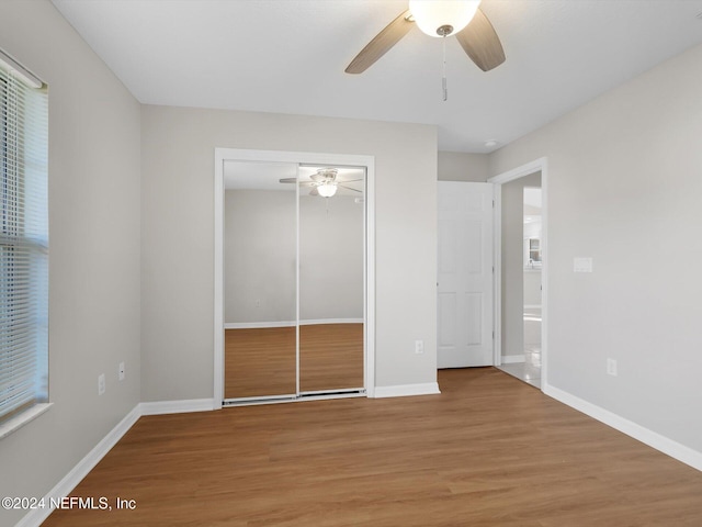 unfurnished bedroom with wood-type flooring, a closet, and ceiling fan