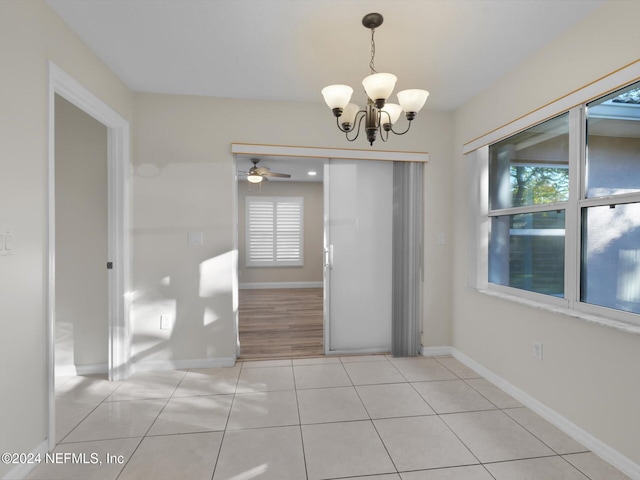 unfurnished dining area with ceiling fan with notable chandelier and light tile patterned floors