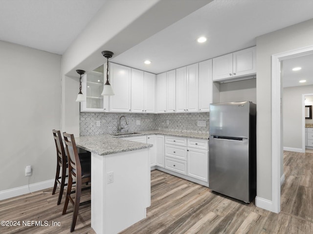 kitchen with white cabinetry, stainless steel refrigerator, and sink