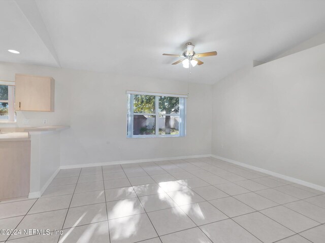 empty room featuring ceiling fan, light tile patterned flooring, and a wealth of natural light