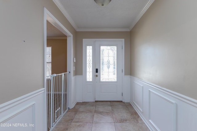 entrance foyer featuring ornamental molding, a textured ceiling, and light tile patterned floors