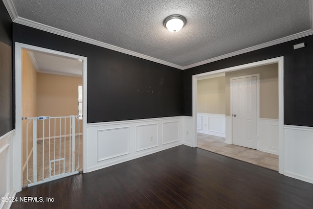 empty room with hardwood / wood-style floors, a textured ceiling, and ornamental molding